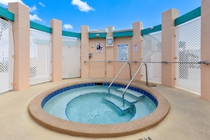 Een hottub met betegelde rand, omgeven door beige wanden en witte lattenpanelen.