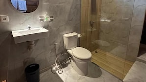 Een moderne badkamer met een douchecabine van glas, een toilet en een wastafel.