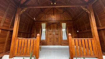 A wooden porch with a bench, a set of double doors, and a small step leading up to the entrance.