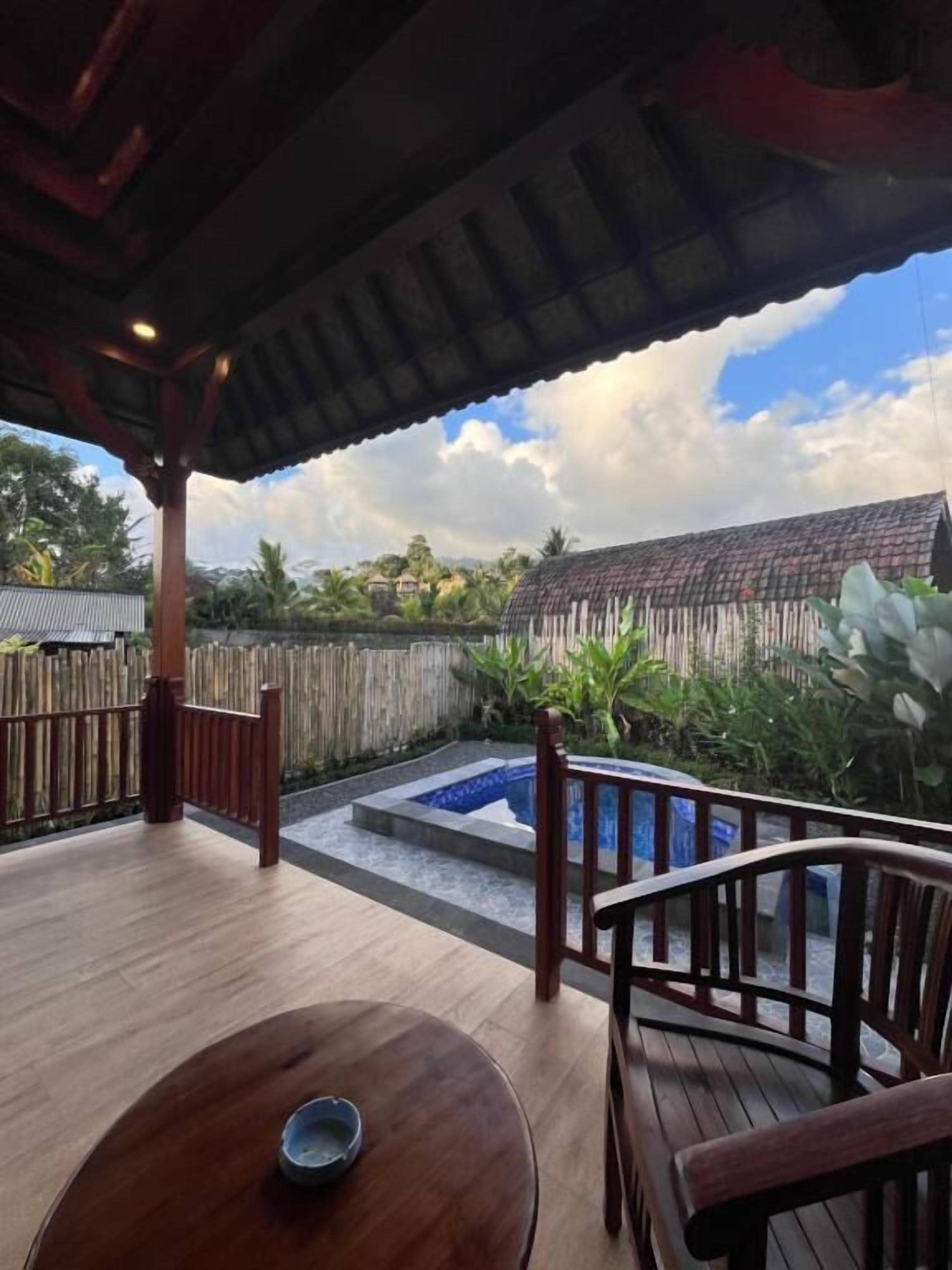 A wooden deck with a table and chairs, a small pool, and a view of the surrounding area.