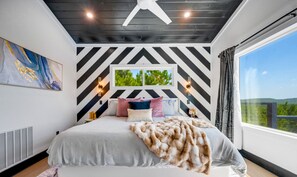 Ein Schlafzimmer mit einem Bett, einem großen Fenster und einem Deckenventilator.