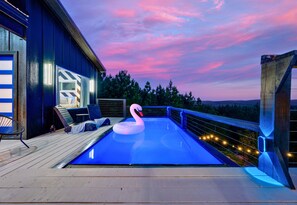 A swimming pool with a swan float, deck chairs, and a view of the landscape. - Mountain Views | EV Charger | Pool | Speakeasy (Broken Bow)