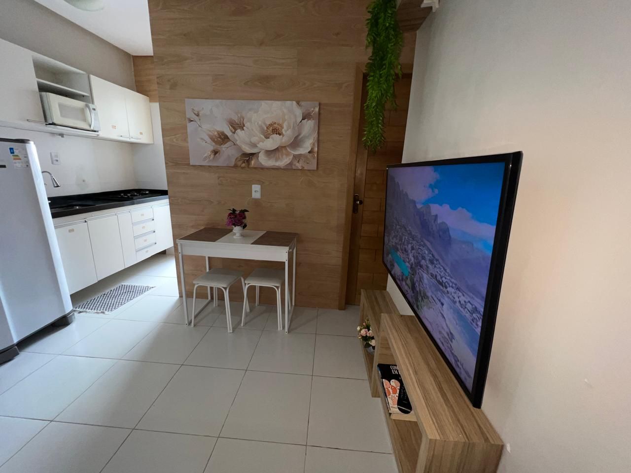 Una cocina moderna con armarios blancos, microondas y comedor con mesa y sillas.