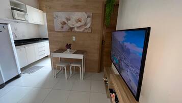 Una cocina moderna con armarios blancos, microondas y comedor con mesa y sillas.