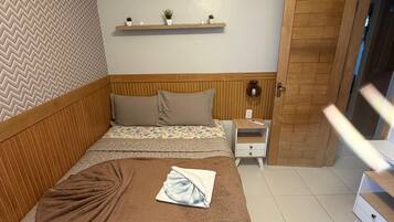 Un dormitorio con cama, mesitas de noche, cabecera de madera, pared con diseño de espiga y una puerta.