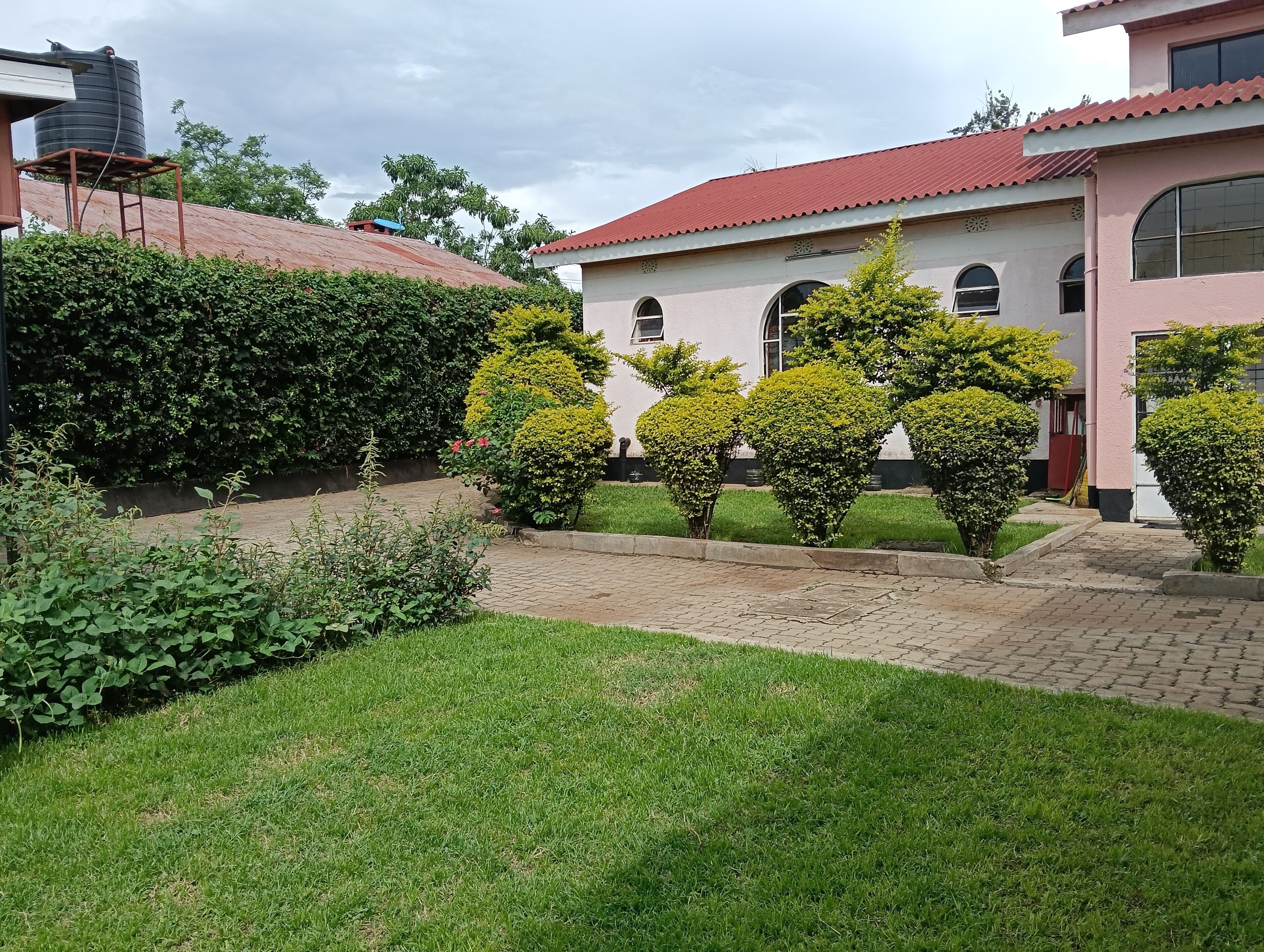 A building with a red roof, surrounded by well-maintained hedges and a grassy area.