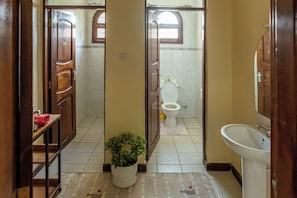 Un bagno con il water, un lavandino e una pianta in vaso.