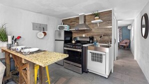 Een compacte keuken met een houten aanrecht, roestvrijstalen apparatuur en een kleine eethoek.