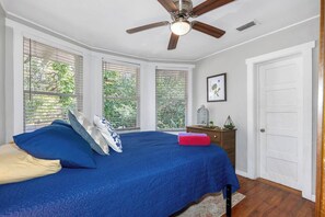 A bedroom with a bed, a ceiling fan, a window with blinds, and a door. - Double Waterfront Estate; 12 Beds, Kayaks, Firepit (Tampa)