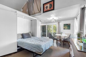 A modern bedroom with a bed, a dining area with a table and chairs, and a sliding glass door leading to a balcony. - Double Waterfront Estate; 12 Beds, Kayaks, Firepit (Tampa)