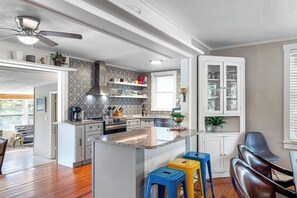 A modern kitchen with a central island, built-in appliances, and a dining area with a view. - Double Waterfront Estate; 12 Beds, Kayaks, Firepit (Tampa)