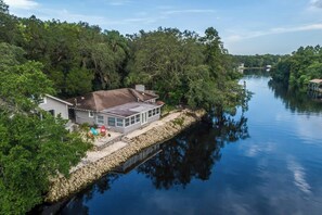 A house with a dock extending into a calm river, surrounded by dense trees. - Double Waterfront Estate; 12 Beds, Kayaks, Firepit (Tampa)