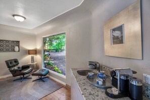 A modern bathroom with a sink, countertop, and a coffee machine.
