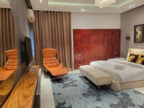Ein Hotelzimmer mit einem Bett, einem Sofa, einem Sessel, einem Kleiderschrank und einem Fernseher.