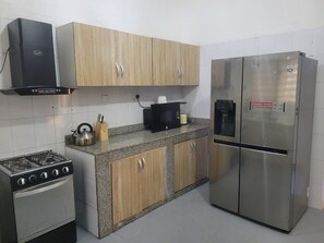 A kitchen with a gas stove, microwave, refrigerator, and wooden cabinets. - 4 units of 2bedroom building in gorgeous Lagos with AC and fitness room (Lagos)
