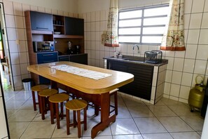 Une cuisine dotée d’un îlot central, de tabourets, d’un évier, de placards et d’une fenêtre avec des rideaux.