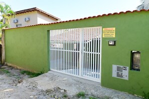 A gated entrance with a metal gate, a sign prohibiting parking, and a utility box on a green wall. - Casa do Curral | A home close to everything! (Ilhabela)