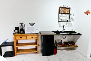 A compact kitchenette with a microwave, coffee maker, and a small refrigerator. - Jubarte Chalés | Suite with waterfall (Ilhabela)