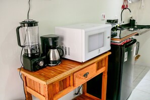 A kitchen counter with a coffee maker, a blender, and a microwave. - Jubarte Chalés | Confort near the beach (Ilhabela)