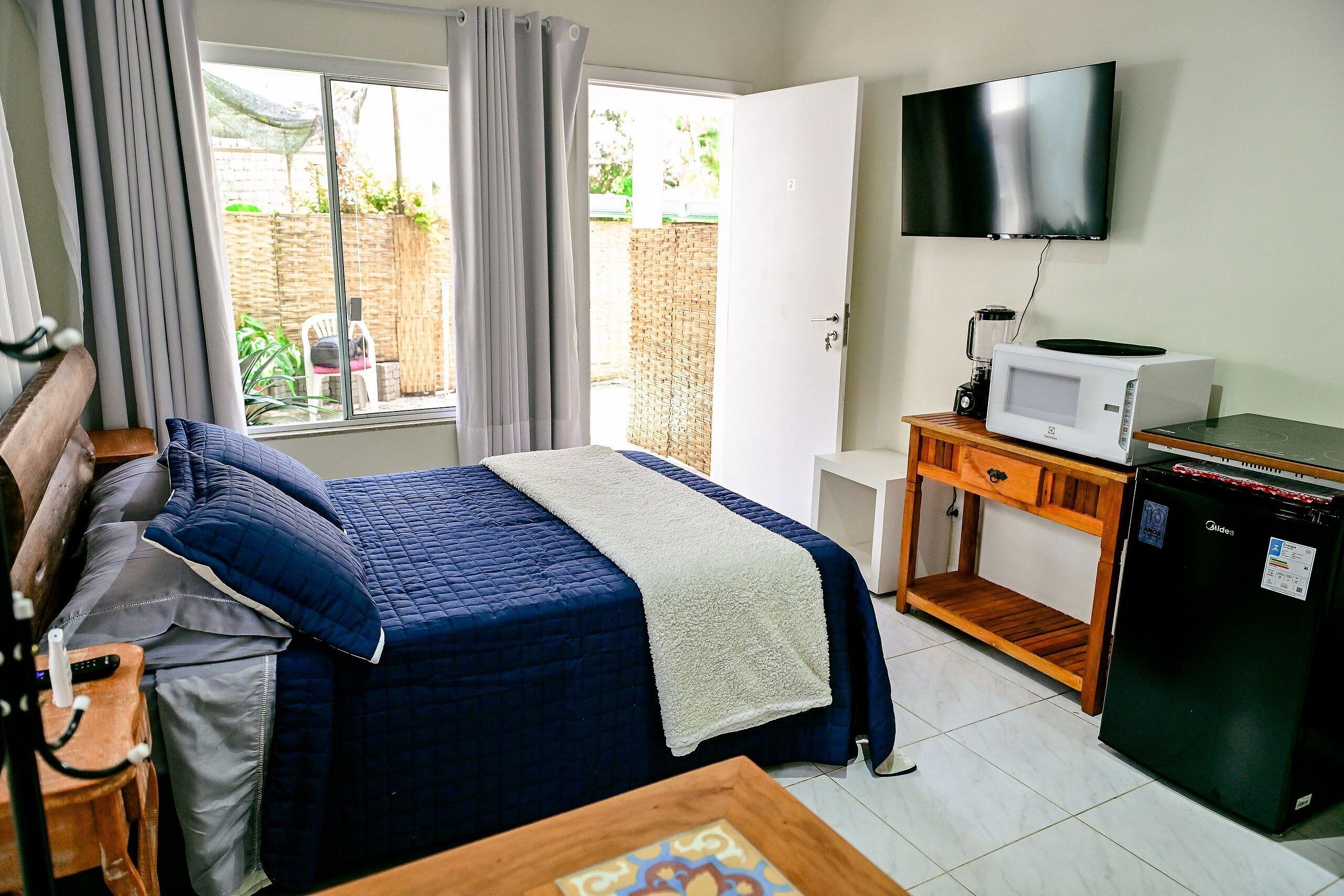 A hotel room with a bed, a television, a microwave, and a refrigerator.