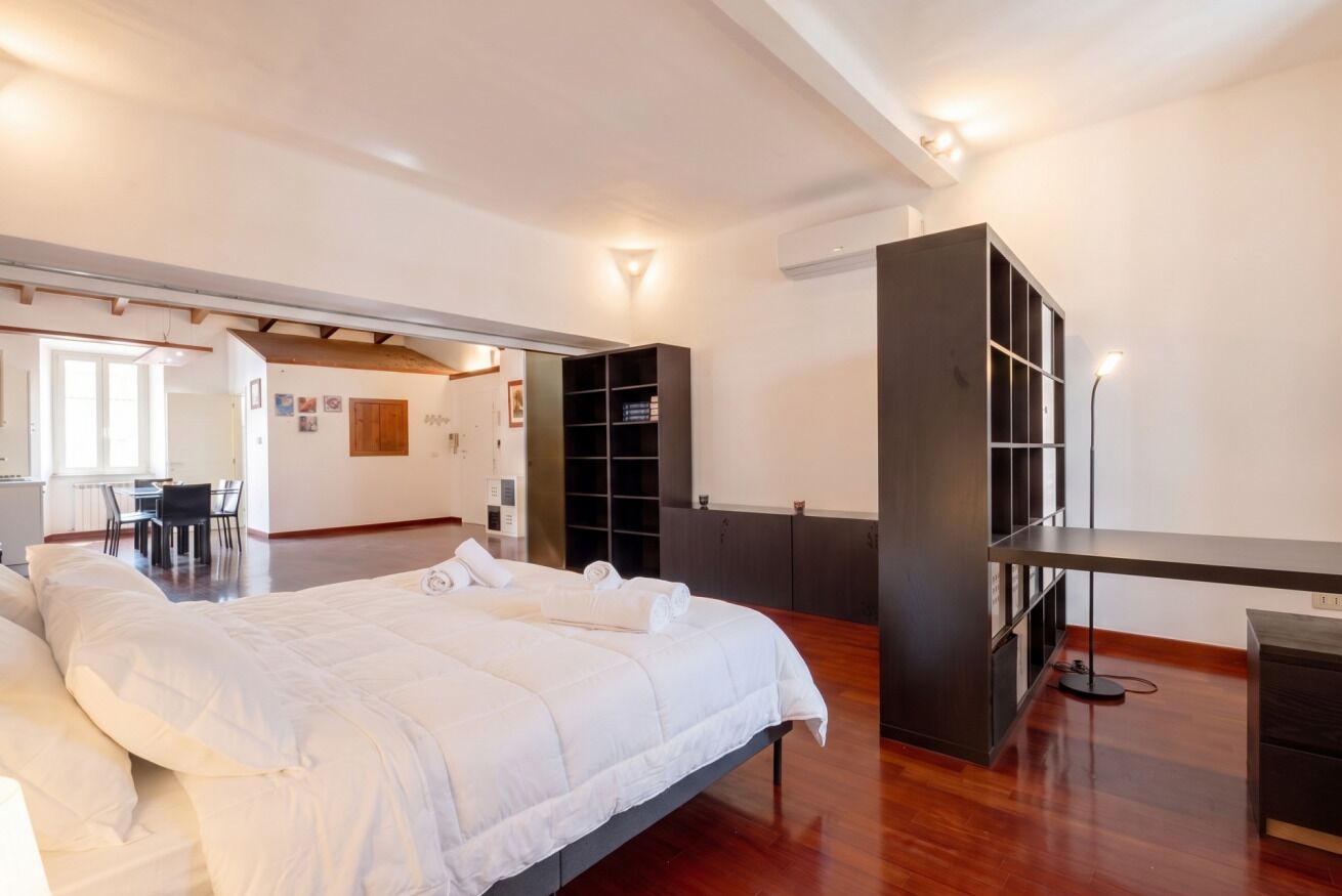 A hotel room with a large bed, a desk, and a wardrobe.