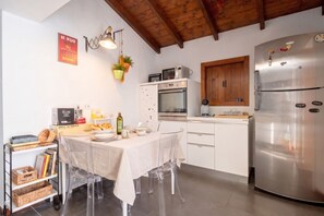 A modern kitchen with a dining table, stainless steel appliances, and a wooden ceiling. - Murat Wooden House | Rustic Charm in Central Bari (Bari)