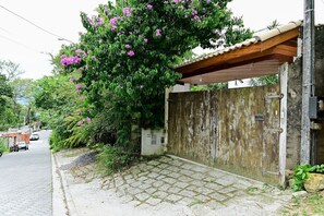 Un'area residenziale con vialetto lastricato che conduce a un ingresso con cancello, una motocicletta parcheggiata e un'auto sulla strada.