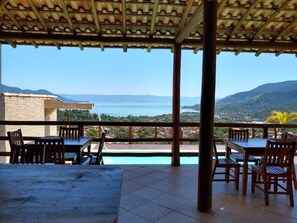 An outdoor terrace with a view of a body of water and mountains.