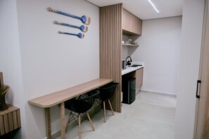 A modern kitchen with a wooden countertop, black chairs, and a built-in dishwasher.