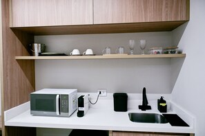 A compact kitchen with a microwave, a kettle, a toaster, and a sink.