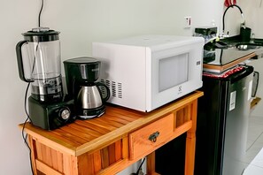 Eine Küche mit Mikrowelle, Kaffeemaschine und Mixer auf einem Holztisch.