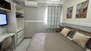 Un dormitori amb un llit, un escriptori i una televisió.