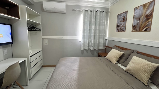 A bedroom with a bed, a desk, and a television. - 403 Apto Versátil e Aconchegante (Belém)