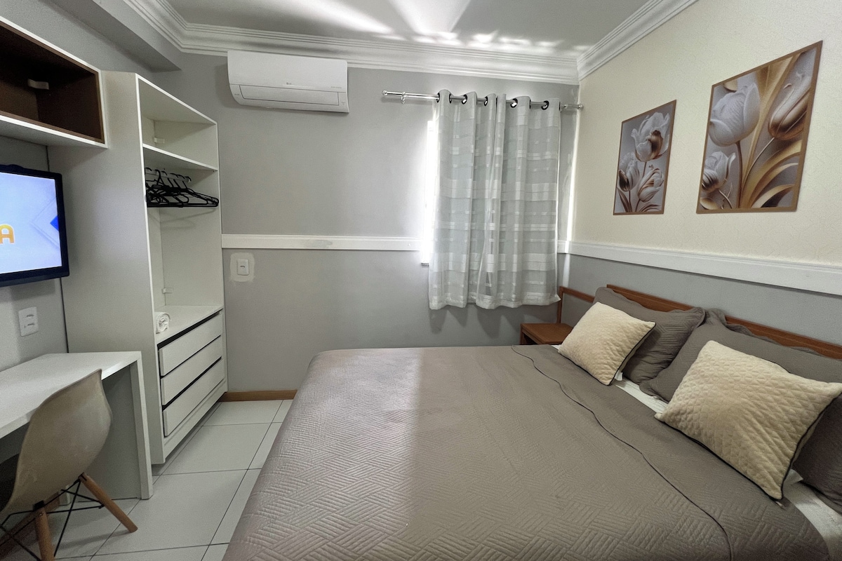 A bedroom with a bed, a desk, and a television.