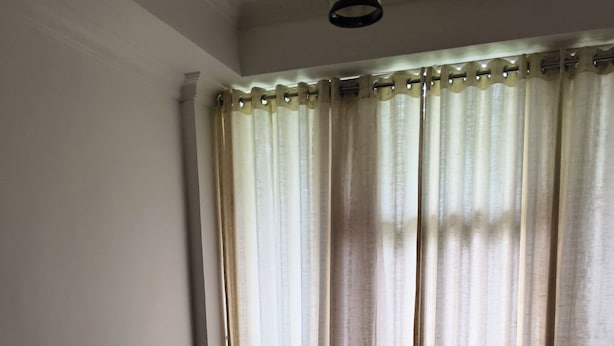 A room with a sofa, a small table, and a window with curtains.