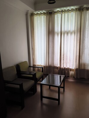 A room with a sofa, a small table, and a window with curtains.