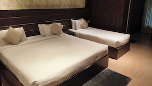 A hotel room with two beds, a dark headboard, a textured wall, and a wooden floor.