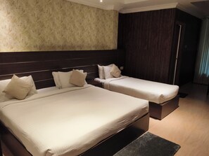A hotel room with two beds, a dark headboard, a textured wall, and a wooden floor. - Matha Residency Munnar (Devikolam)