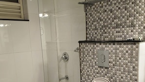 A bathroom with a toilet, a shower, and a tiled wall.