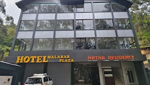 A modern hotel building with a sign for 'HOTEL MALABAR PLAZA' and 'MATHA RESIDENCY'.