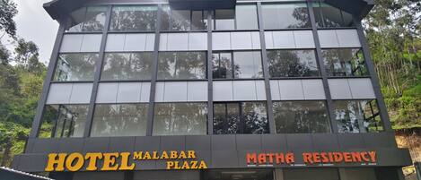 A modern hotel building with a sign for 'HOTEL MALABAR PLAZA' and 'MATHA RESIDENCY'.