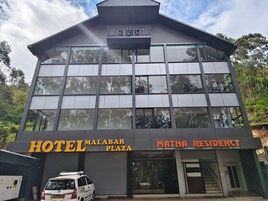 Un moderno edificio de hotel con un letrero que dice 'HOTEL MALABAR PLAZA' y 'MATHA RESIDENCY'.