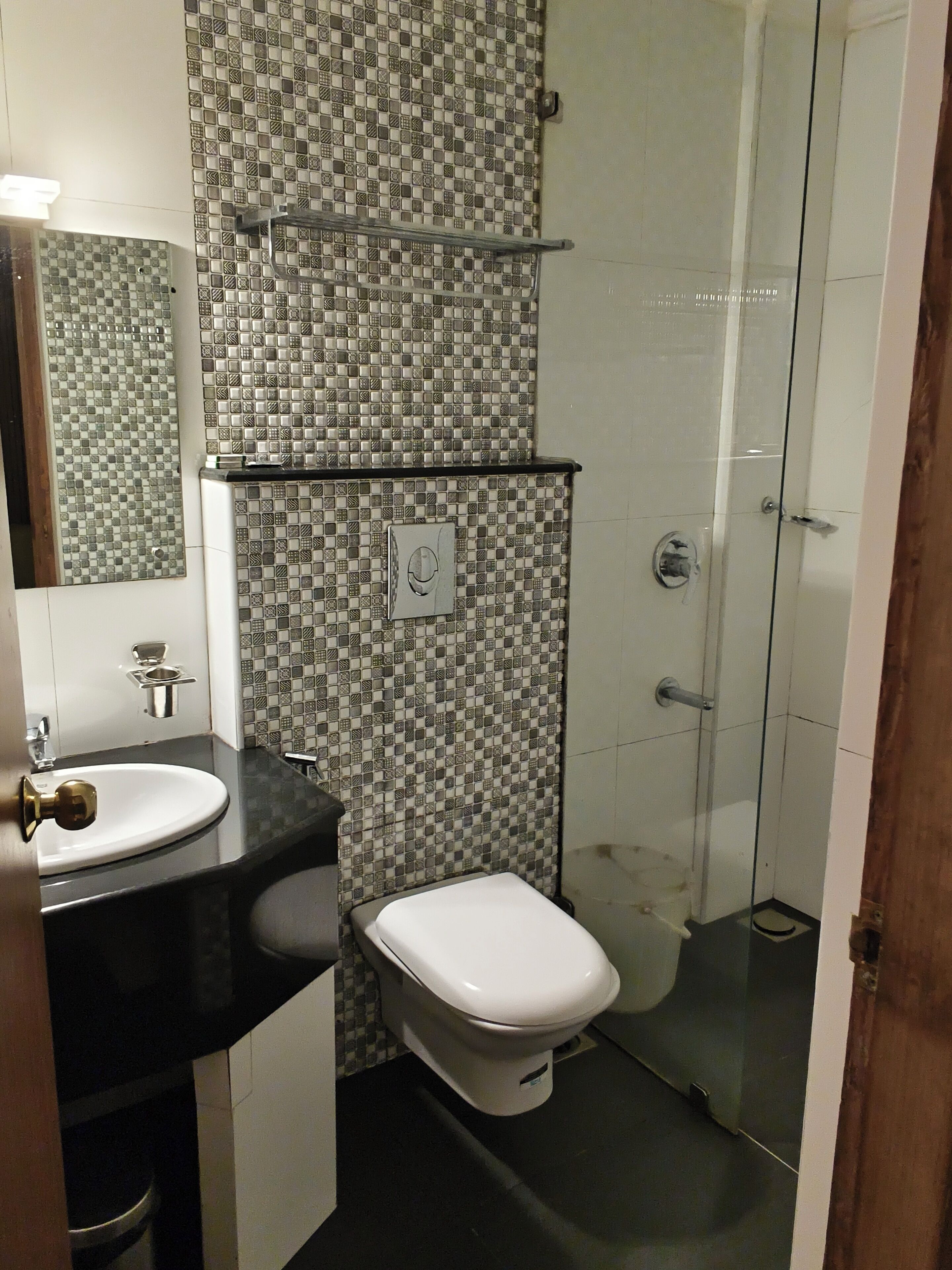 Un baño con pared de azulejos, lavamanos, inodoro y zona de ducha.