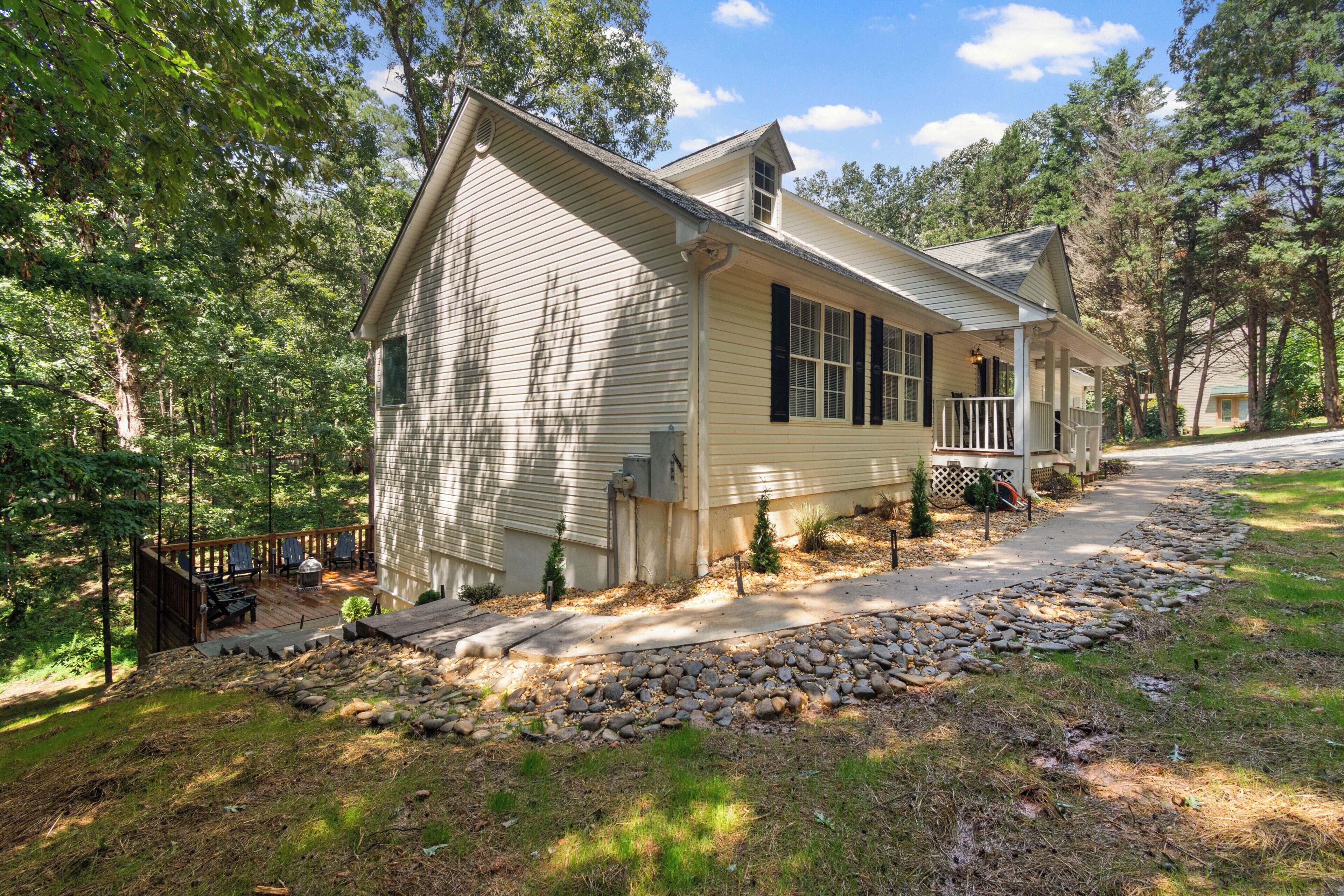 A single-story house with a front porch, a small deck, and a stone pathway leading to the entrance.