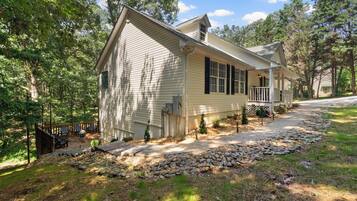 A single-story house with a front porch, a small deck, and a stone pathway leading to the entrance.