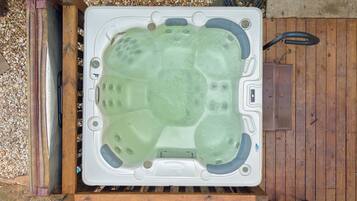 A hot tub on a wooden deck with a surrounding pebble area.