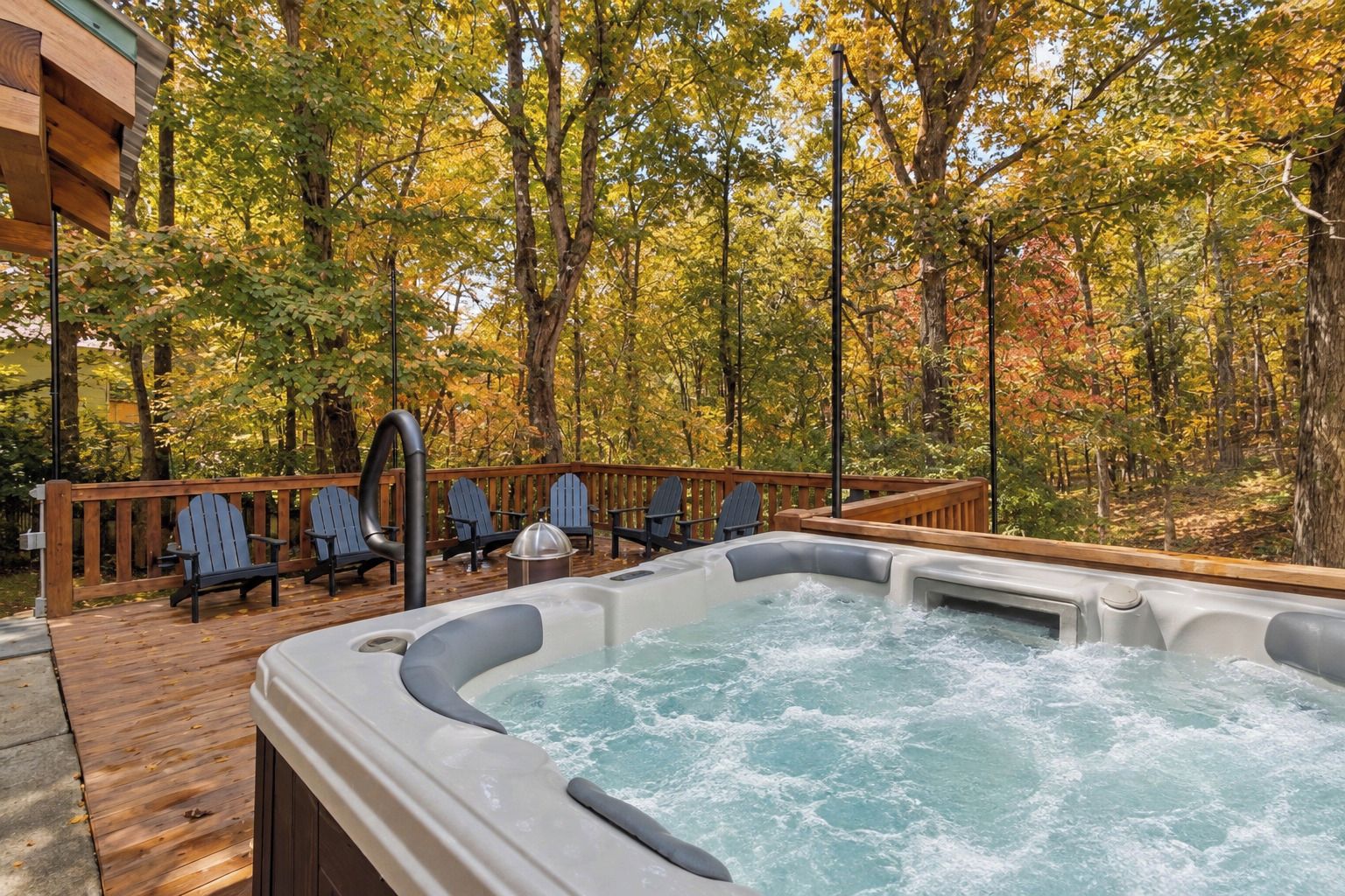 Een hottub op een houten terras, omringd door herfstbomen.