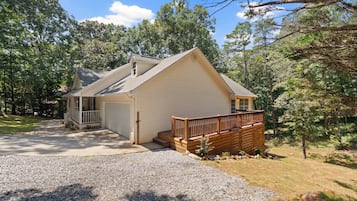 A single-story house with a front porch, a garage, and a wooden deck.