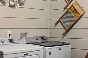 A laundry area with two washing machines and a drying rack.