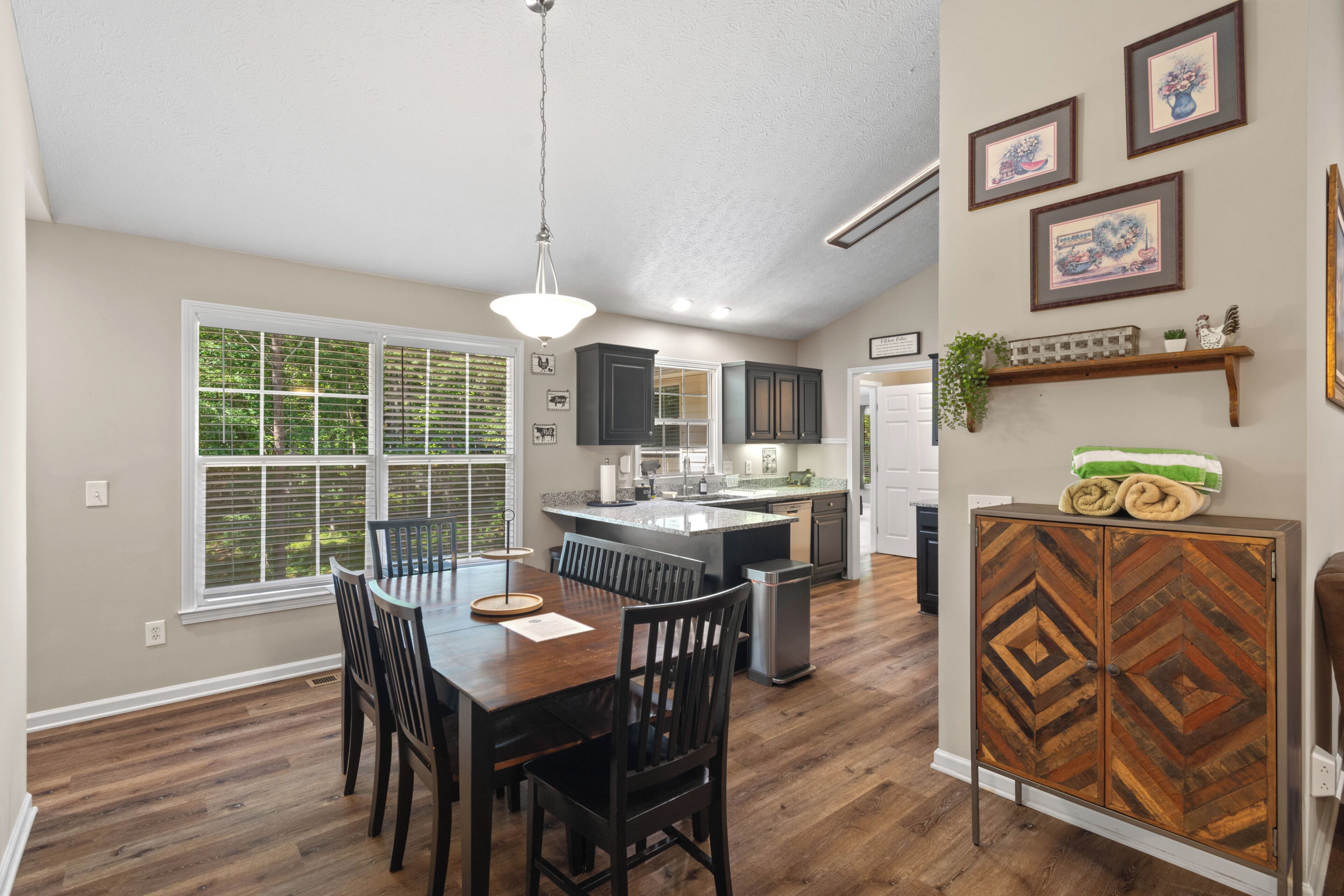 A modern kitchen with a central island, wooden dining table, and chairs.